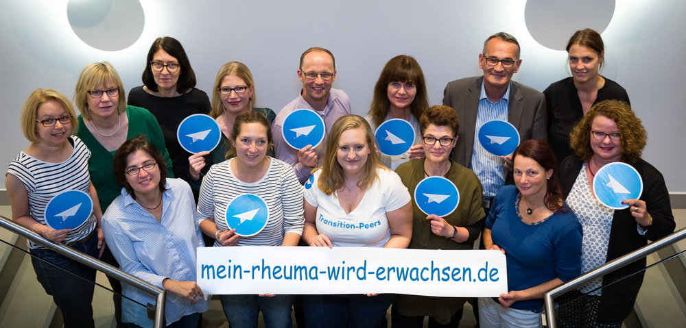 Gruppe hält Logo von "mein Rheuma wird erwachsen" in die Luft transition Worshop
