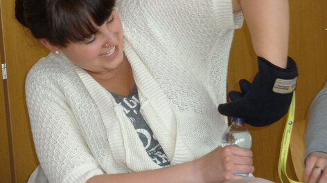 Frau mit Rheumahandschuh öffnet Flasche